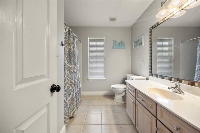 bathroom with tile patterned floors, vanity, a healthy amount of sunlight, and toilet