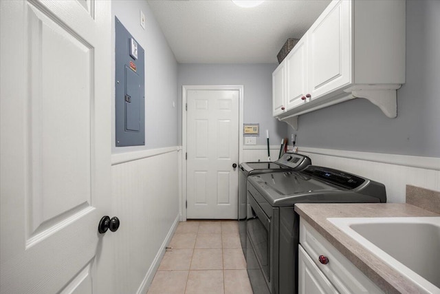 laundry area featuring electric panel, cabinets, light tile patterned flooring, independent washer and dryer, and sink