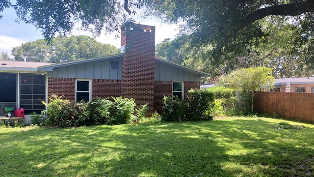 view of home's exterior featuring fence, a yard, brick siding, and board and batten siding