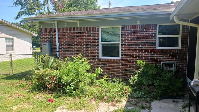 view of side of home featuring brick siding and fence