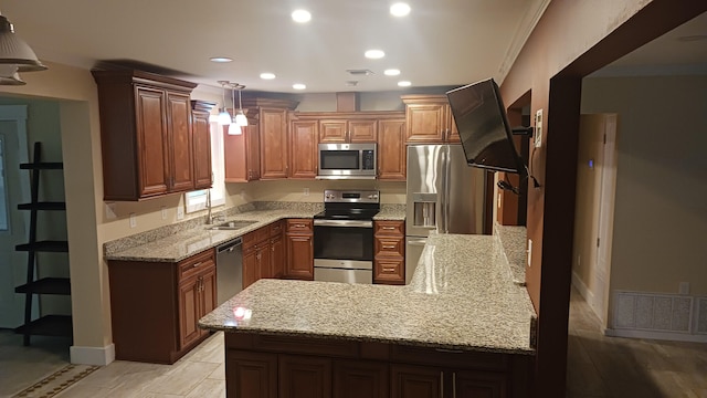 kitchen with visible vents, a sink, light stone counters, appliances with stainless steel finishes, and a peninsula