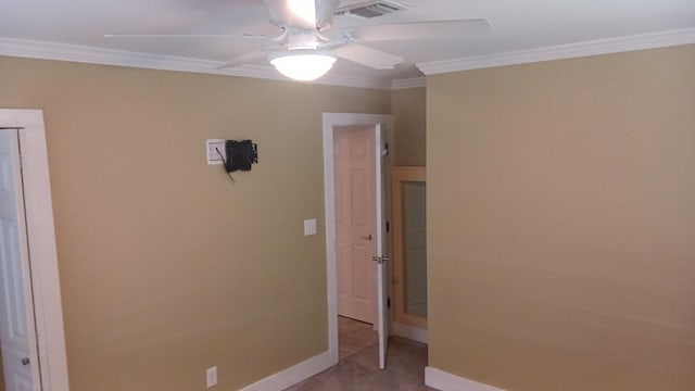 empty room with crown molding, a ceiling fan, visible vents, and baseboards