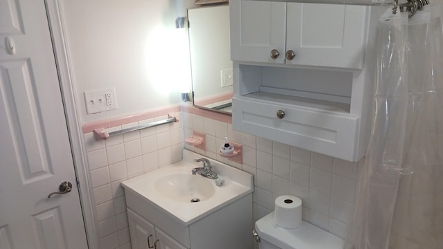 bathroom with a wainscoted wall, toilet, tile walls, and vanity