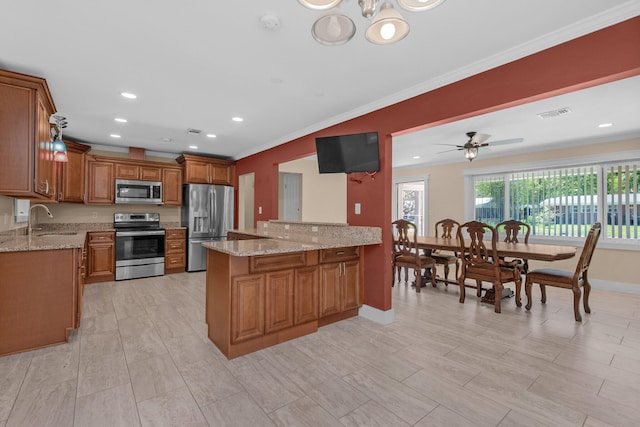 111 NW Sotir St, Fort Walton Beach, FL 32548 - kitchen featuring a sink, appliances with stainless steel finishes, a peninsula, brown cabinets, and light stone counters