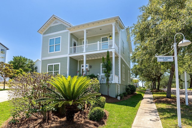 view of front of property featuring a balcony, covered porch, and a front lawn