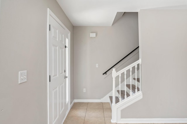 entrance foyer with light tile patterned floors, stairs, and baseboards