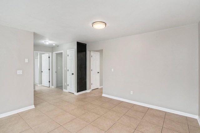 spare room featuring baseboards and light tile patterned floors