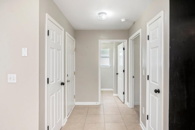 hallway with light tile patterned floors and baseboards