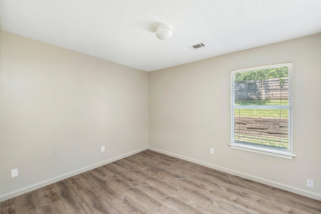 spare room featuring light hardwood / wood-style flooring and a textured ceiling