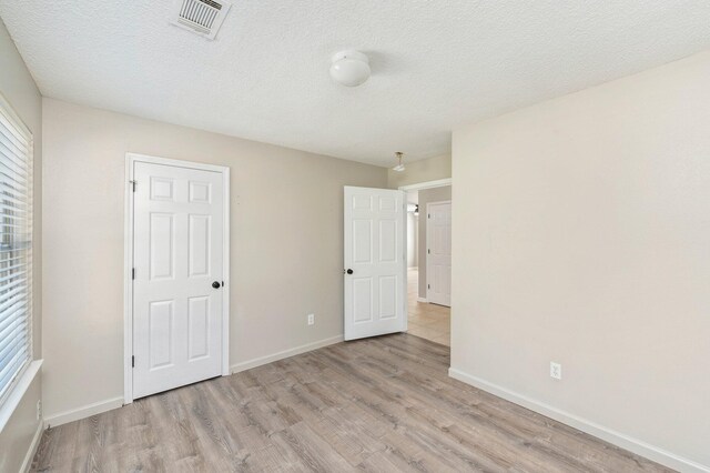 unfurnished bedroom featuring light hardwood / wood-style floors and a textured ceiling