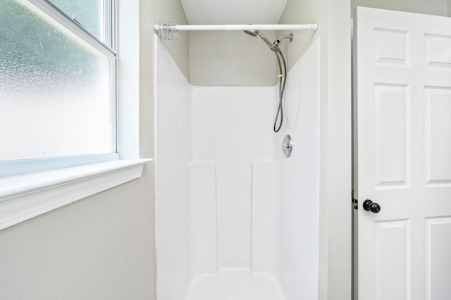 bathroom with a shower and a textured ceiling