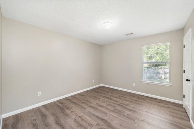 unfurnished room featuring hardwood / wood-style flooring and a textured ceiling