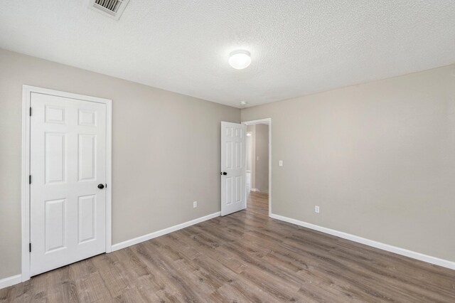 unfurnished room featuring wood-type flooring and a textured ceiling