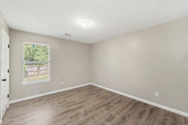 unfurnished room with a textured ceiling and wood-type flooring