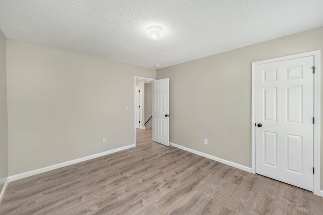 unfurnished room with a textured ceiling and light hardwood / wood-style floors