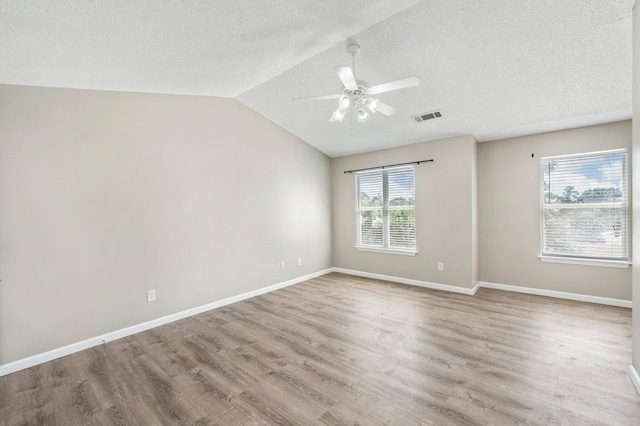 unfurnished room featuring light hardwood / wood-style floors, a textured ceiling, vaulted ceiling, and ceiling fan