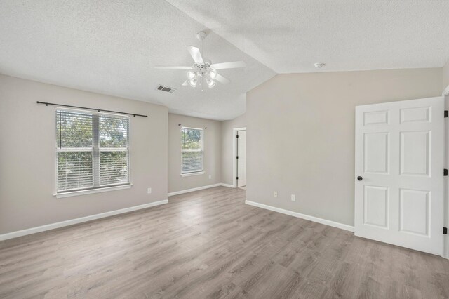 empty room with ceiling fan, a textured ceiling, vaulted ceiling, and light wood-type flooring