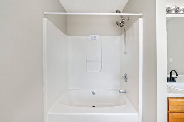 bathroom with vanity, a textured ceiling, and tub / shower combination