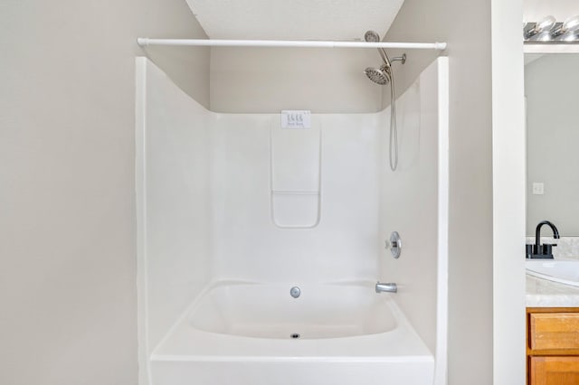 bathroom featuring a textured ceiling, bathing tub / shower combination, and vanity