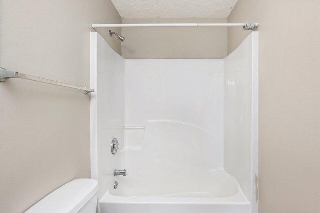 full bath with toilet, a textured ceiling, and bathing tub / shower combination