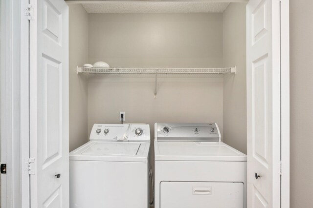 clothes washing area with a textured ceiling and washing machine and clothes dryer