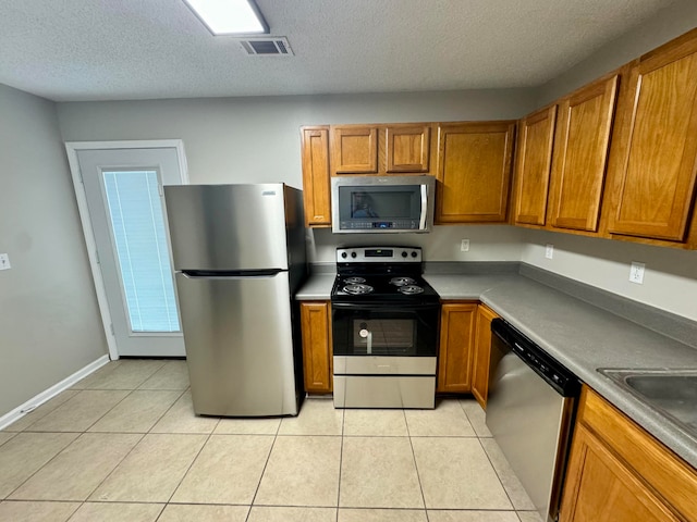 kitchen featuring a textured ceiling, light tile patterned flooring, and stainless steel appliances