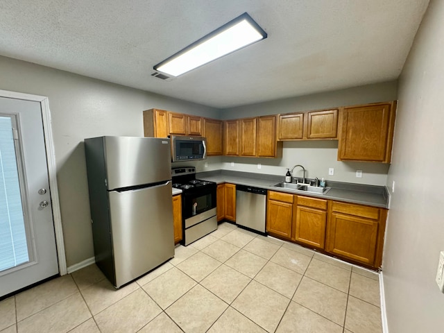 kitchen featuring a textured ceiling, stainless steel appliances, sink, and light tile patterned floors