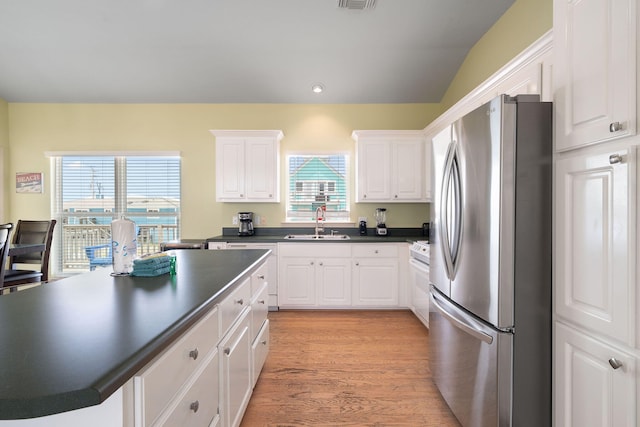 kitchen with sink, a center island, stainless steel refrigerator, light hardwood / wood-style floors, and white cabinets