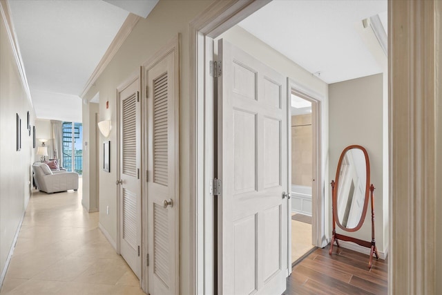 hall with ornamental molding, light wood-style floors, and baseboards