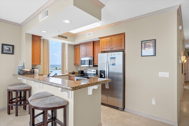 kitchen with appliances with stainless steel finishes, a breakfast bar area, visible vents, and crown molding