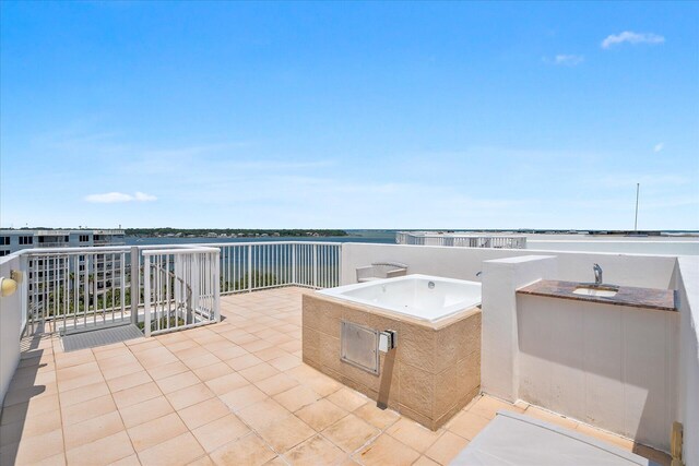 view of patio / terrace with a water view, a sink, and a balcony