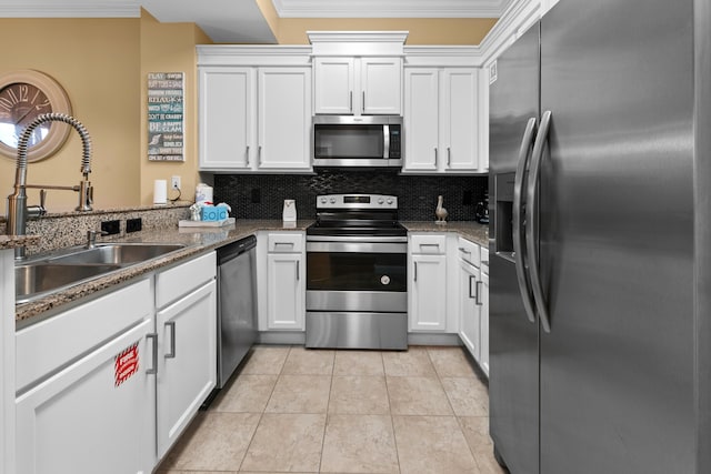 kitchen with appliances with stainless steel finishes, white cabinets, backsplash, ornamental molding, and sink