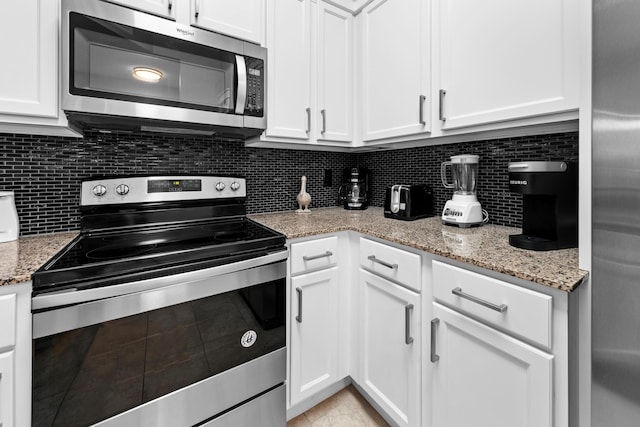 kitchen featuring appliances with stainless steel finishes, white cabinetry, and light stone countertops