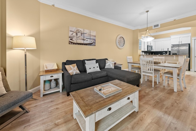 living room with crown molding and light hardwood / wood-style flooring