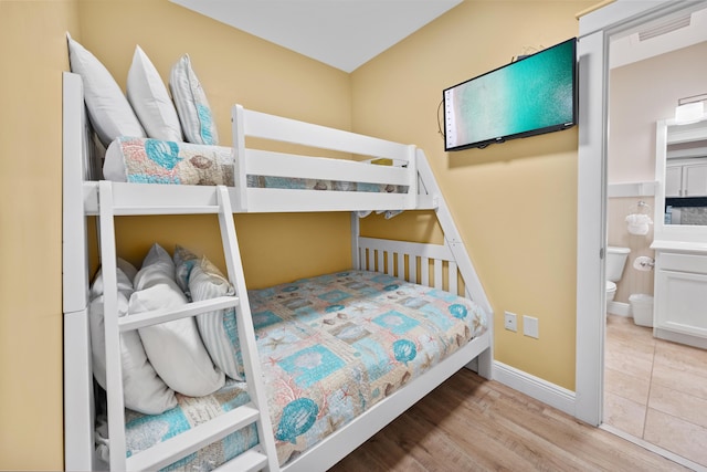 bedroom featuring light hardwood / wood-style floors and ensuite bathroom