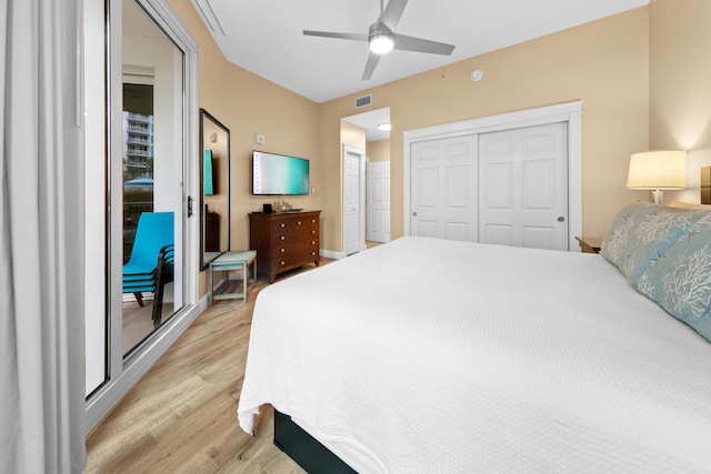 bedroom with light hardwood / wood-style floors, ceiling fan, and two closets