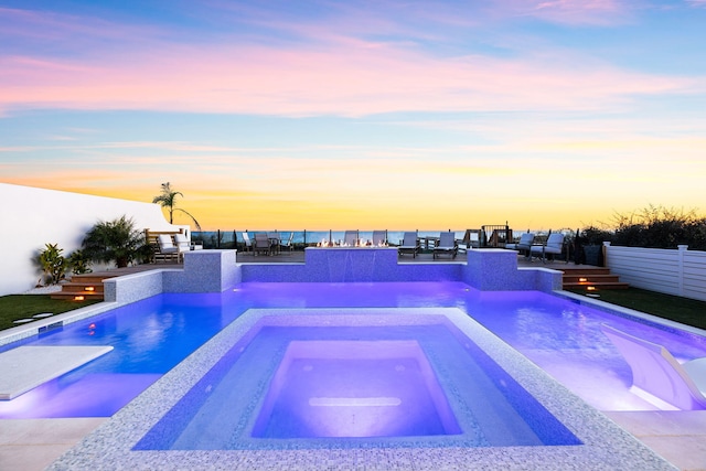 pool at dusk featuring an in ground hot tub