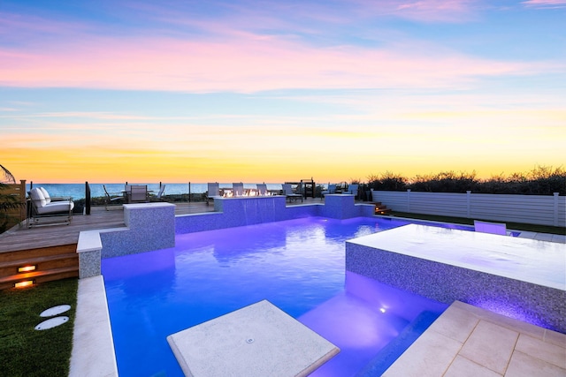 pool at dusk with a water view and pool water feature