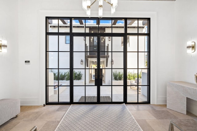 entryway with light tile patterned flooring, french doors, and an inviting chandelier