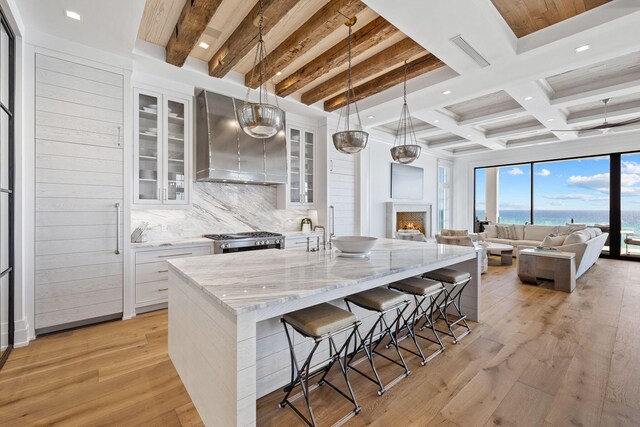 kitchen featuring beam ceiling, light hardwood / wood-style floors, white cabinets, and decorative light fixtures