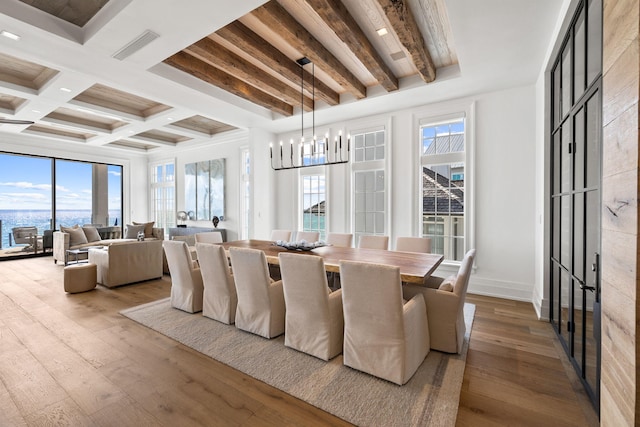 dining area featuring beamed ceiling, plenty of natural light, a notable chandelier, and hardwood / wood-style flooring