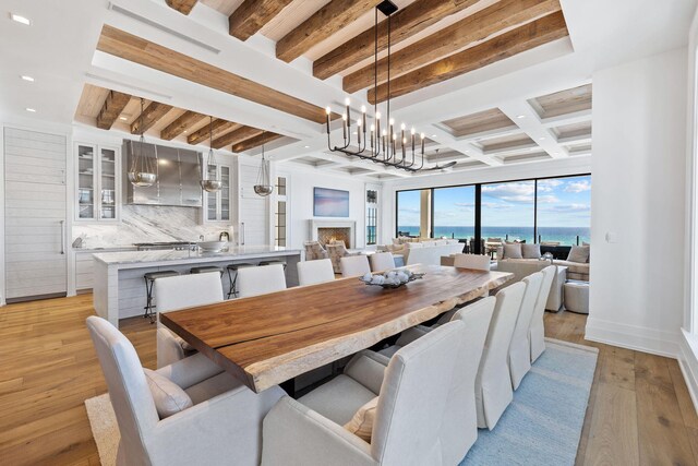 dining room with beamed ceiling, light hardwood / wood-style flooring, and an inviting chandelier