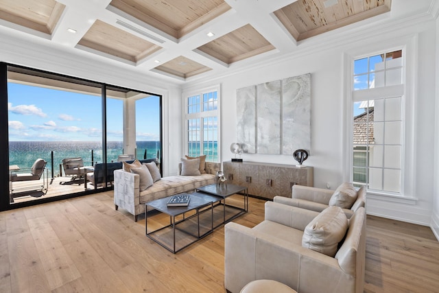 living room with coffered ceiling, a water view, ornamental molding, and light hardwood / wood-style floors