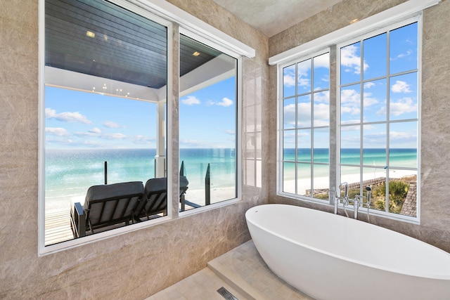 bathroom with tile walls, a water view, and a beach view