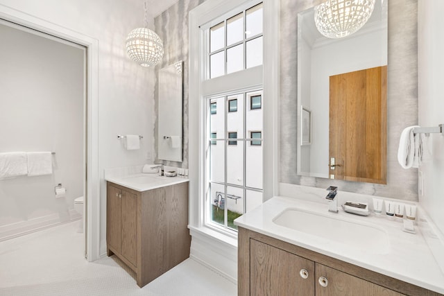 bathroom with a notable chandelier, vanity, and toilet