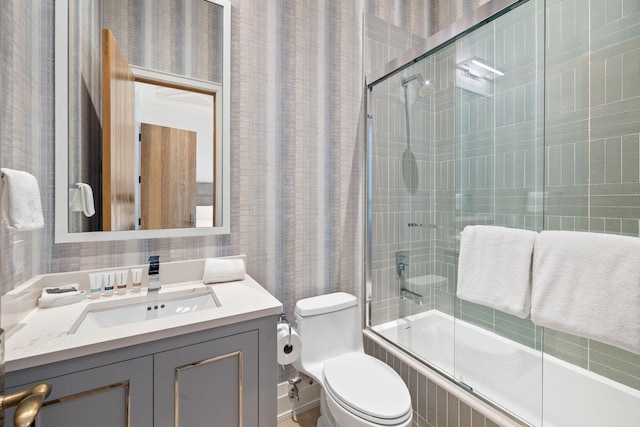 full bathroom with vanity, tile walls, bath / shower combo with glass door, and toilet