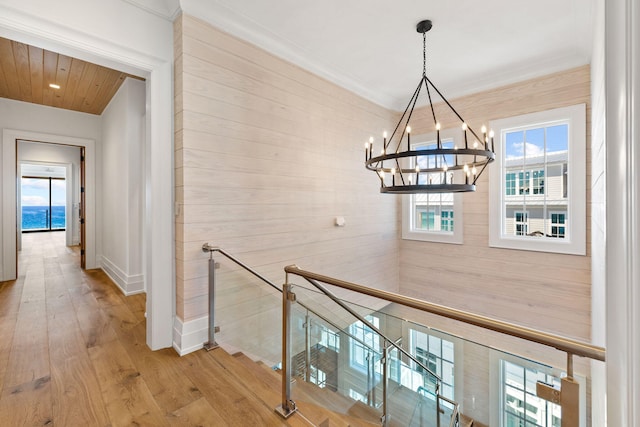 hall featuring light hardwood / wood-style flooring, a water view, crown molding, and a chandelier