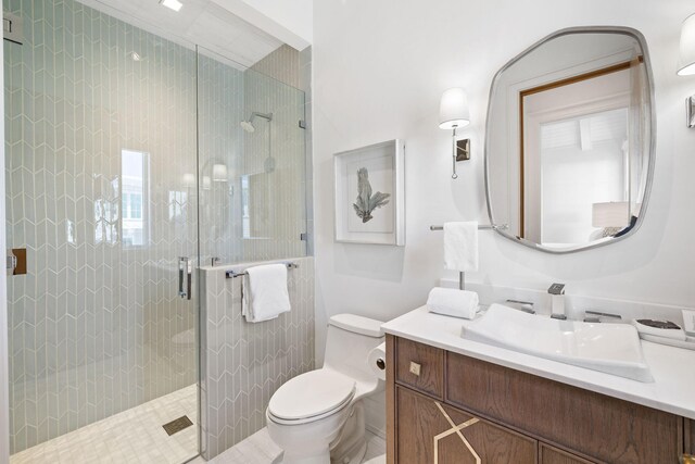 bathroom with a shower with door, vanity, and toilet