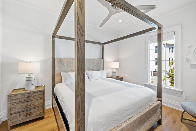 bedroom featuring light wood-type flooring, ornamental molding, and ceiling fan