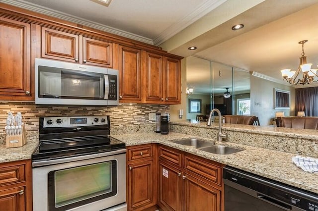 kitchen with a sink, a chandelier, appliances with stainless steel finishes, brown cabinetry, and ornamental molding